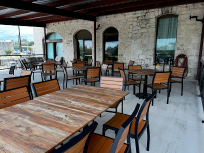 Float The River Brewing Outdoor Patio Seating Outdoor patio seating area at Float The River Brewing with stone walls and wooden tables and chairs.